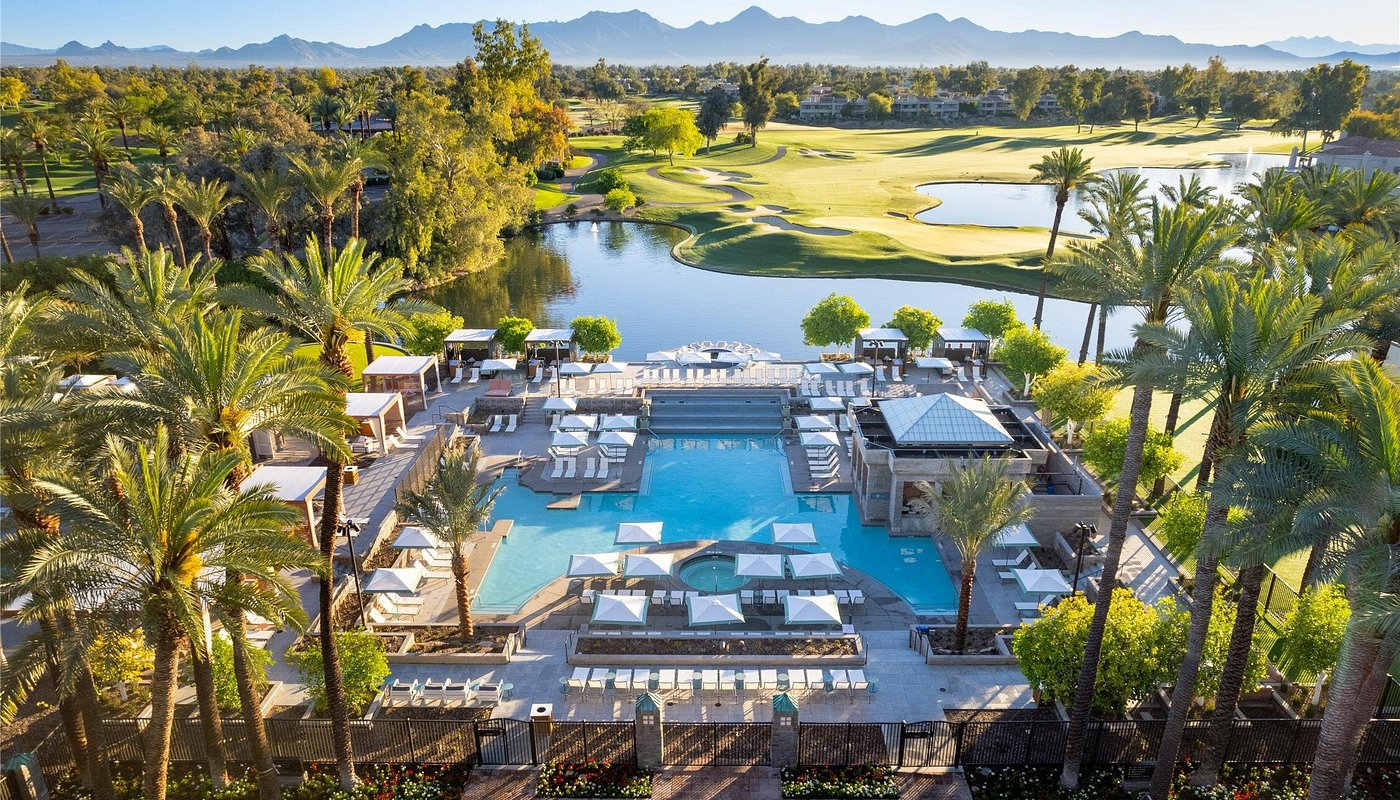 Scottsdale resort pool surrounded by palms, with lake, golf course and mountain views
