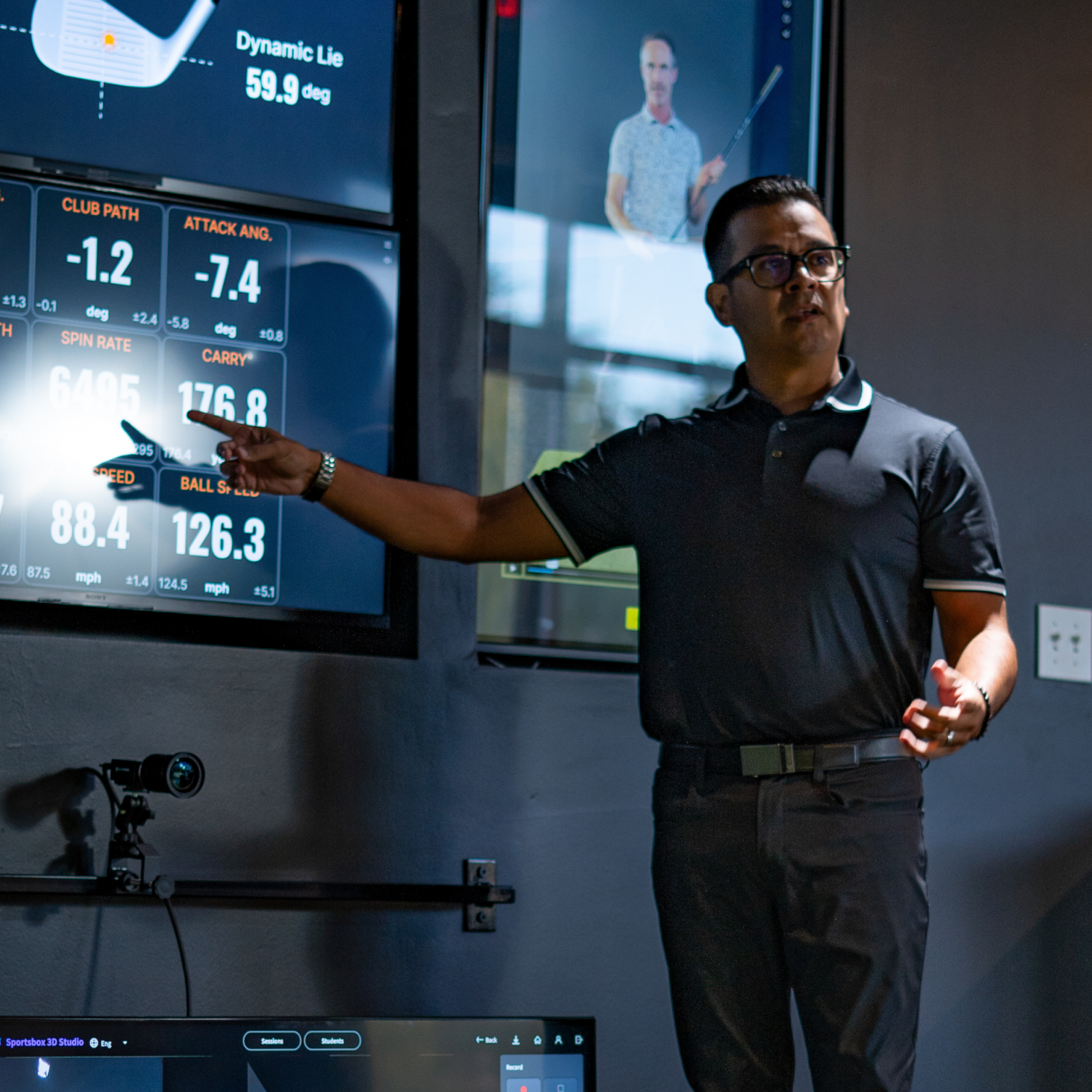 Golf coach reviewing swing data on indoor training screens
